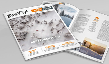 Ein Magazin mit dem Titel „Best of q qq sport“ mit einer aufgeschlagenen Seite, auf der verschneite Landschaften und Artikel zu sehen sind. Das Cover zeigt eine verschneite Waldszene mit dem fettgedruckten Text „Auf Spurensuche“.