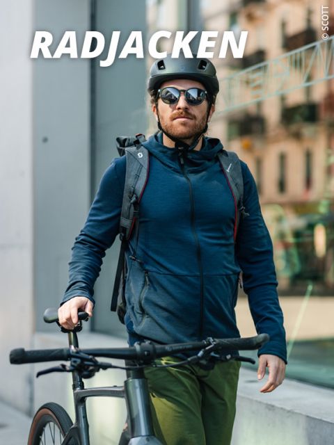 Ein Mann mit Helm, Sonnenbrille und blauer Jacke steht neben einem Fahrrad. Er befindet sich im Freien in einem Stadtgebiet mit modernen Gebäuden im Hintergrund. Oben im Bild erscheint das Wort „RADJACKEN“.