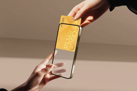 Eine Hand hält ein Smartphone mit transparentem Display, eine andere schiebt eine gelbe Karte mit der Aufschrift „Plus Card“ hinein. Der Hintergrund ist sanft beleuchtet und wirft sanfte Schatten.