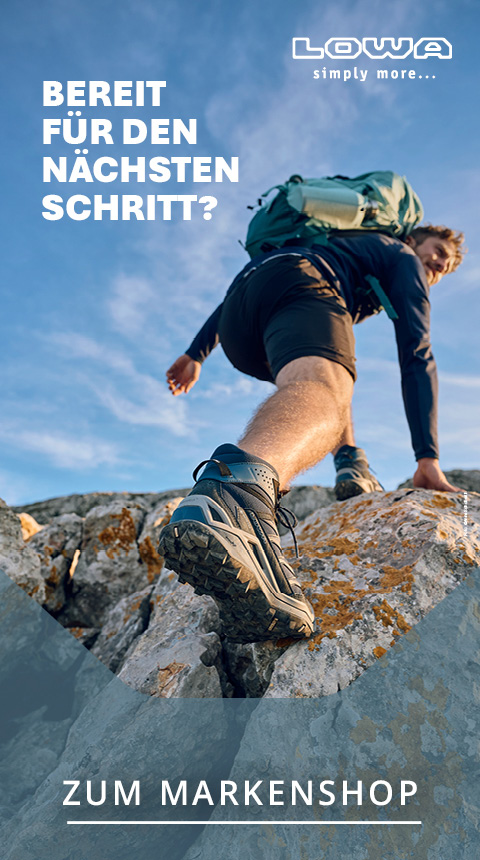 Ein Wanderer mit Outdoor-Ausrüstung und Rucksack klettert unter blauem Himmel über felsiges Gelände. Der Text lautet auf Deutsch: „Bereit für den nächsten Schritt?“, und in der Ecke erscheint das LOWA-Logo.