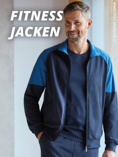 Ein Mann mit kurzen Haaren und einem Bart trägt eine marineblaue und blaue Fitnessjacke mit Reißverschluss, steht in einem Haus und lächelt. Der Text lautet "FITNESS JACKEN" in fetten weißen Buchstaben.