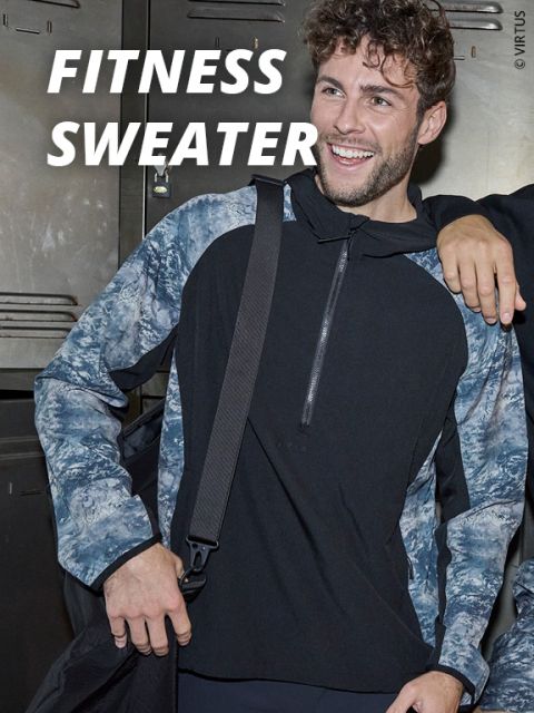 Ein lächelnder Mann, der einen schwarz-grau gemusterten Fitness-Pullover trägt, steht vor Schließfächern und hält einen Taschengurt. Über ihm ist in fetten weißen Buchstaben der Text "Fitness Sweater" zu lesen.