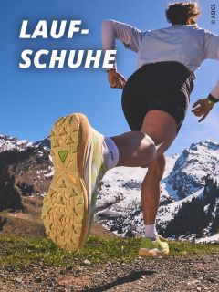 Ein Läufer in Sportkleidung sprintet im Freien auf einem Bergpfad, wobei der Fokus auf seinen Laufschuhen liegt. Im Hintergrund sind schneebedeckte Gipfel und blauer Himmel zu sehen. Der Text "LAUF-SCHUHE" steht in fetten weißen Buchstaben.