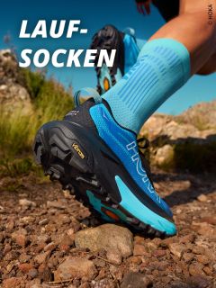 Nahaufnahme einer Person, die im Freien auf einem felsigen Pfad läuft. Sie trägt hellblaue HOKA-Laufschuhe und hellblaue Kompressionssocken. Das Wort "LAUF-SOCKEN" erscheint in fetten weißen Buchstaben in der oberen linken Ecke.
