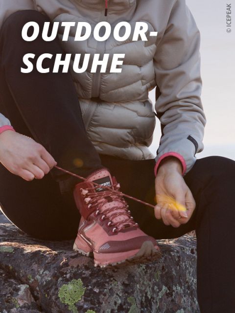 Eine Person in einer hellen Jacke und einer schwarzen Hose sitzt auf einem Felsen und bindet die Schnürsenkel eines braunen Outdoor-Wanderschuhs. Auf dem Bild ist der Text "OUTDOOR-SCHUHE" in fetten weißen Buchstaben zu lesen.