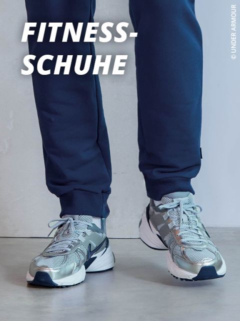 Person in metallisch silbernen und grauen Sportschuhen mit blauen Details, die auf einem hellen Boden steht. Die Person ist mit einer dunkelblauen Hose bekleidet. Der Text "FITNESS-SCHUHE" wird in fetten weißen Buchstaben in der oberen linken Ecke angezeigt.