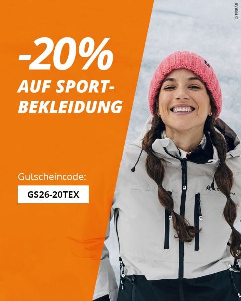 Eine lächelnde Frau in Wintersportkleidung steht im Schnee neben einem orangefarbenen Banner, auf dem 20 % Rabatt auf Sportkleidung mit dem Code GS26-20TEX angeboten wird.