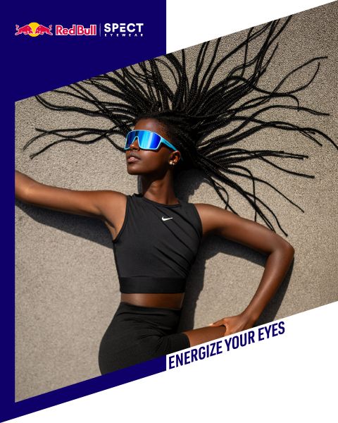 Eine Frau in sportlicher schwarzer Kleidung und blauer, reflektierender Sonnenbrille posiert auf Beton, mit dem Text "Red Bull SPECT Eyewear" und "ENERGIZE YOUR EYES" auf dem Bild.