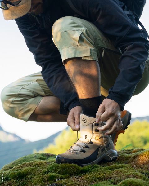 Nahaufnahme von zwei Wanderern, die auf felsigem Gelände stehen, mit Blick auf ihre La Sportiva-Trail-Schuhe unter einem klaren blauen Himmel.