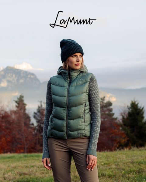 Drei Personen in Winterkleidung fahren unter klarem Himmel Ski durch eine verschneite Berglandschaft. Der Text lautet: „LaMunt MOUNTAIN ME-TIME“. Im Hintergrund sind schneebedeckte Gipfel zu sehen.