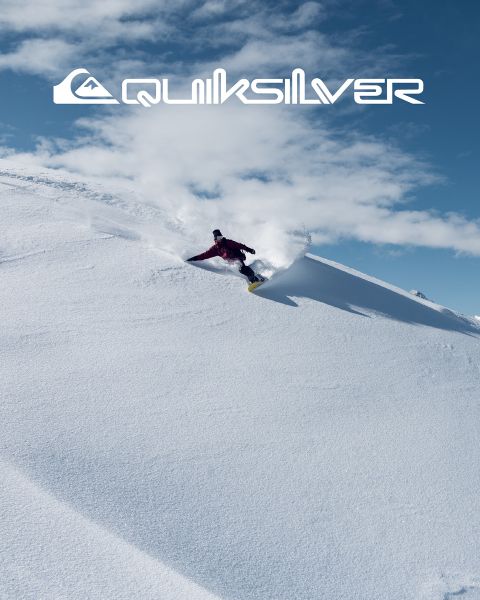 Ein Surfer reitet auf einer großen türkisfarbenen Welle und verkörpert Balance und Können. Er trägt dunkle Badeshorts, und die Welle kräuselt sich über ihm. Über ihm ist das Quiksilver-Logo zu sehen.